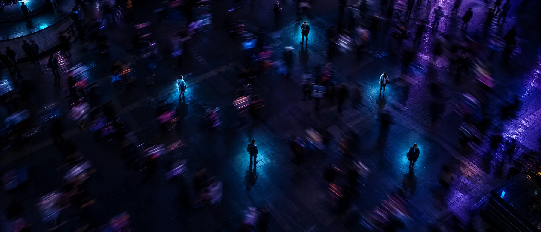 Overhead view of a crowded plaza at night with a few people highlighted